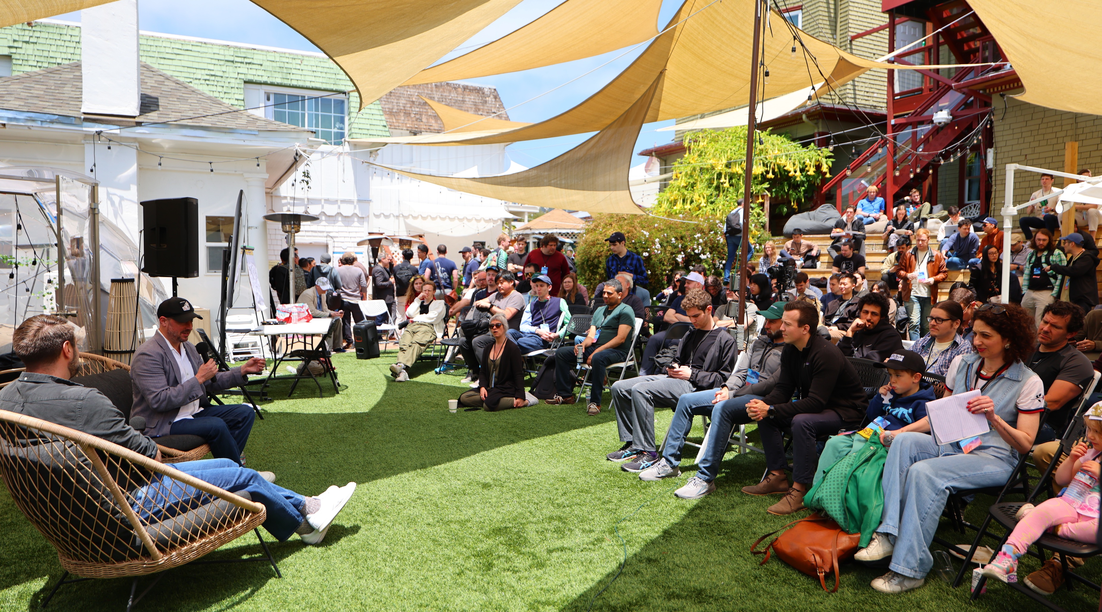 Attendees gathered under sunshade canopies at Manifest